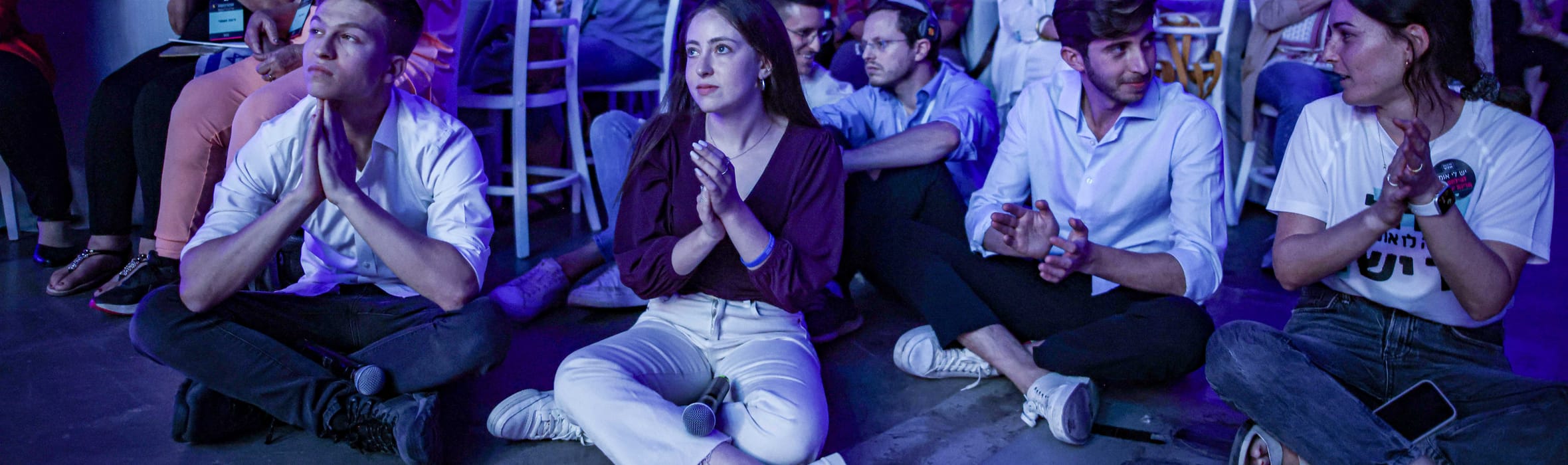 משתתפים בוועידת האומץ יושבים וצופים, צעירים בחזית וקהל מגוון מאחור